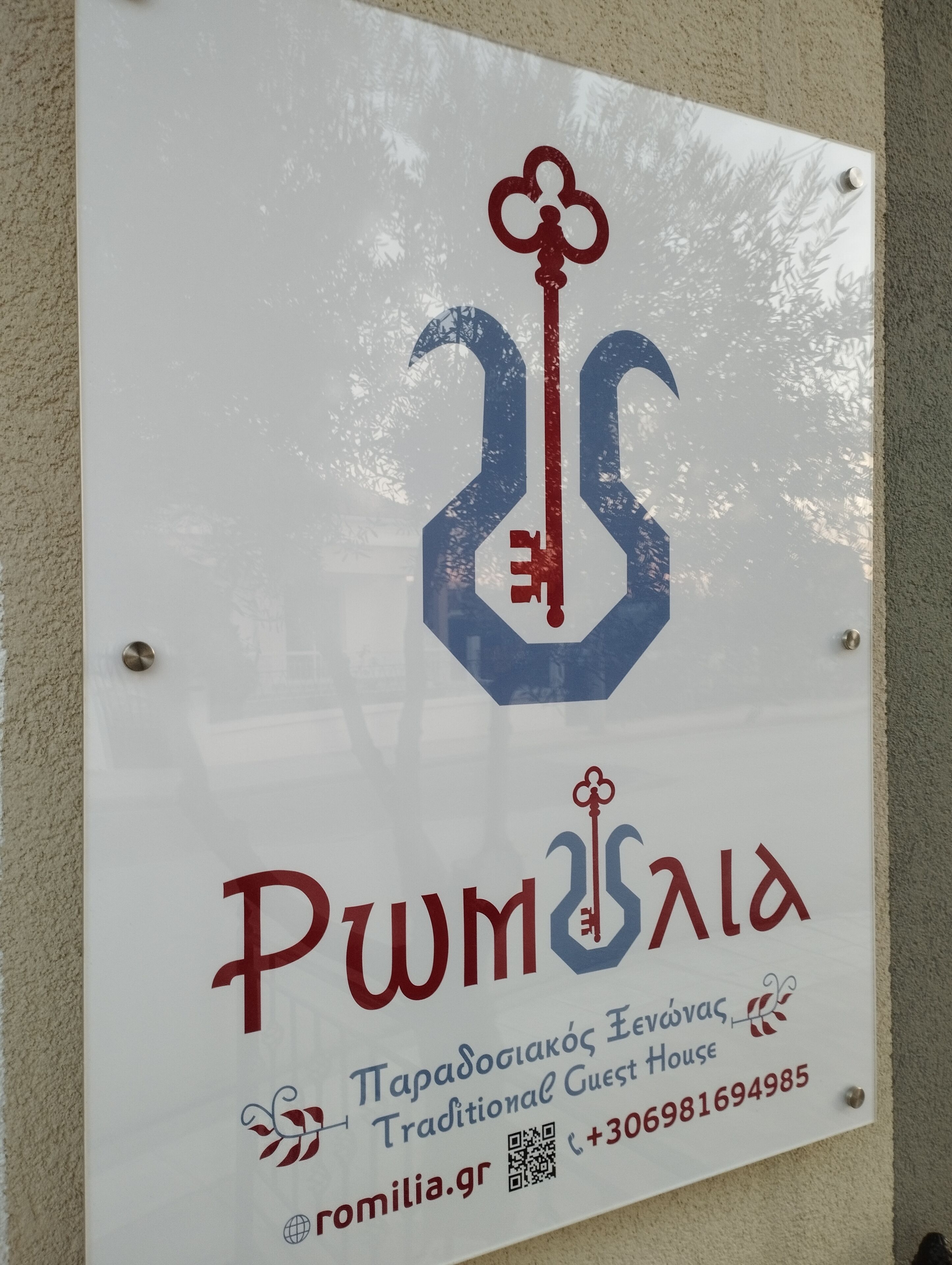 A sign for a traditional guest house with a logo featuring a key and the name 'Pwmisald'. It includes contact information and a QR code.