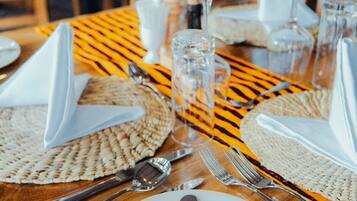 Une table mise pour un repas, avec une bougie, des verres propres et un set de table en fibres tressées.