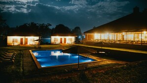 Ein Schwimmbeckenbereich bei Nacht, im Hintergrund ein Gebäude.
