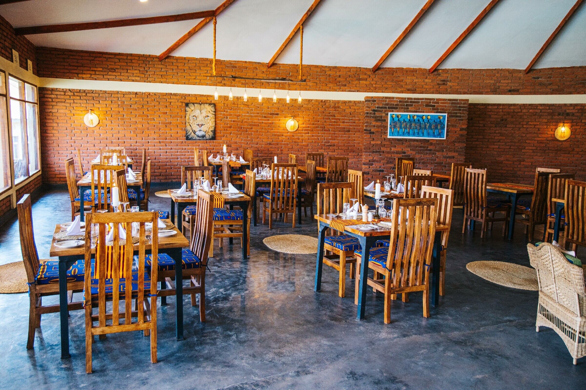 A restaurant with brick walls, wooden tables and chairs, and hanging lights.