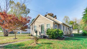 A single-story house with a front porch, a mailbox, and a small front yard with a tree and shrubbery.