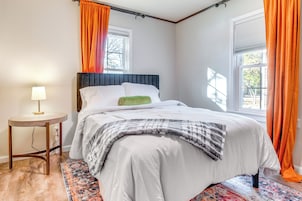 Un dormitorio con cama, mesita de noche y ventana con cortinas.