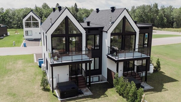 Ein modernes, zweistöckiges Haus mit großen Fenstern und einem Balkon.