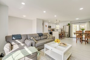 Un salon moderne avec un canapé, une table basse et une vue sur la cuisine.