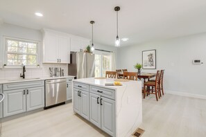 A modern kitchen with white cabinets, stainless steel appliances, and pendant lighting. - Near Top Attractions: Deck Dining at Severn Home! (Severn)