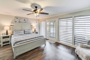 A bedroom with a bed, nightstands, a ceiling fan, and large windows with blinds. - Lake Gem: Private Dock & Large Patio in Lewisville (Little Elm)