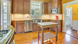 A kitchen with wooden cabinets, a stainless steel sink, a microwave, and a window with curtains. - 1 Mi to Dtwn Meridian: Historic Home w/ Porch! (Meridian)