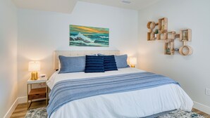 Une chambre à coucher comprenant un lit, des tables de chevet, un ventilateur de plafond, un tableau et des étagères fixées au mur.