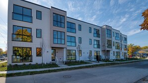 Un immeuble résidentiel moderne à plusieurs étages, doté de grandes fenêtres et d’un toit plat.