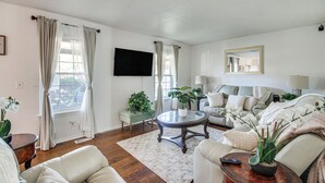 Una sala de estar con sofá, sillón, mesa de centro y plantas en macetas.