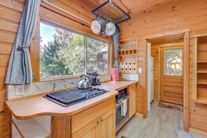 Una cocina compacta con armarios de madera, horno empotrado y ventana con vistas a una terraza.