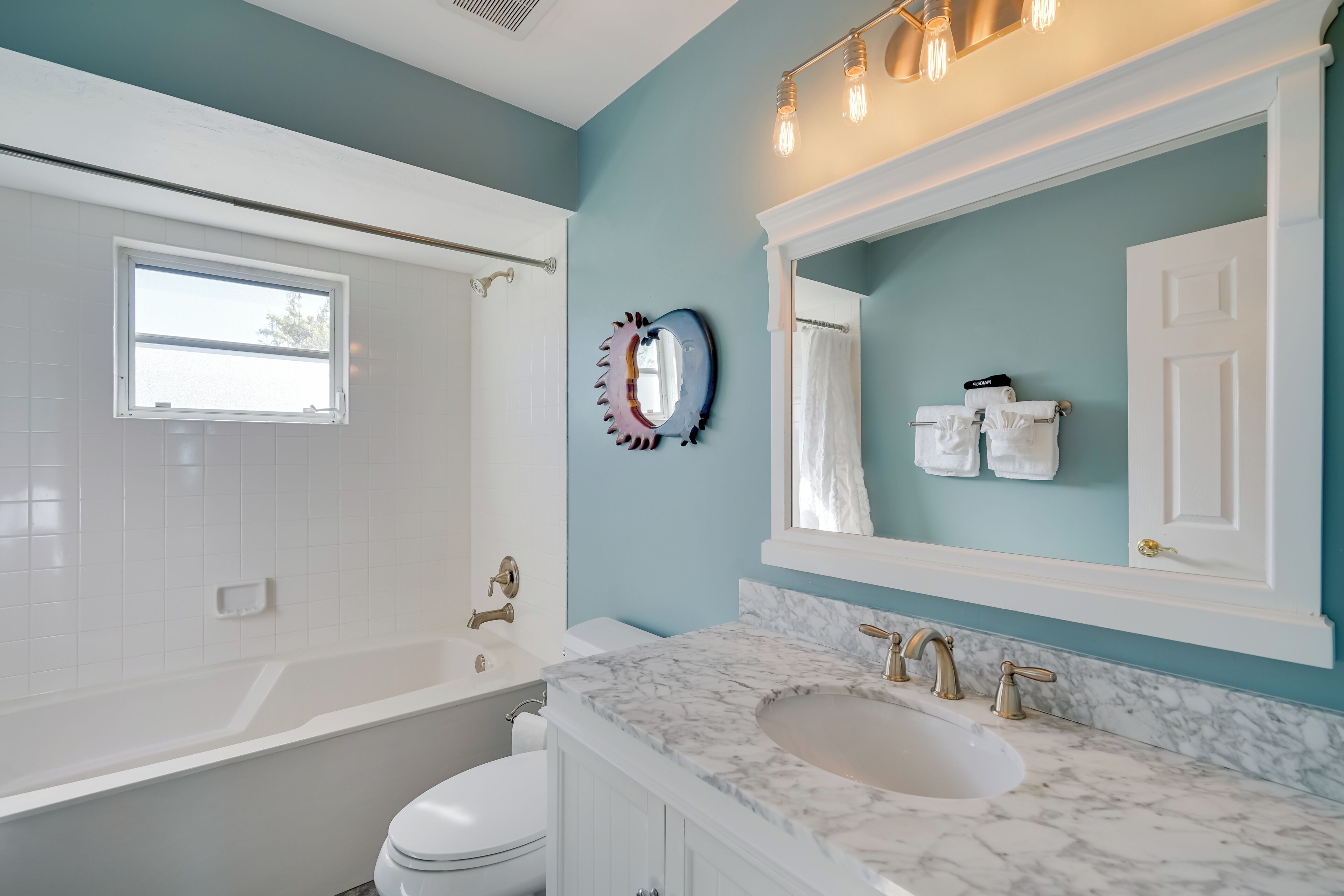 A modern bathroom with a bathtub, a sink, and a mirror.