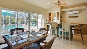 A spacious indoor area with a glass door leading to a pool, wicker furniture, and a ceiling fan. - Laid-back Luxury: Home w/ Pool Near Bowmans Beach (Sanibel)