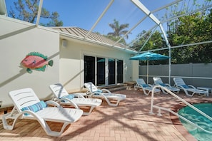 A covered outdoor swimming pool area with lounge chairs and a decorative fish wall. - Laid-back Luxury: Home w/ Pool Near Bowmans Beach (Sanibel)