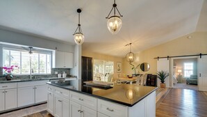 A spacious kitchen with white cabinets, a large island, and pendant lighting. - Laid-back Luxury: Home w/ Pool Near Bowmans Beach (Sanibel)