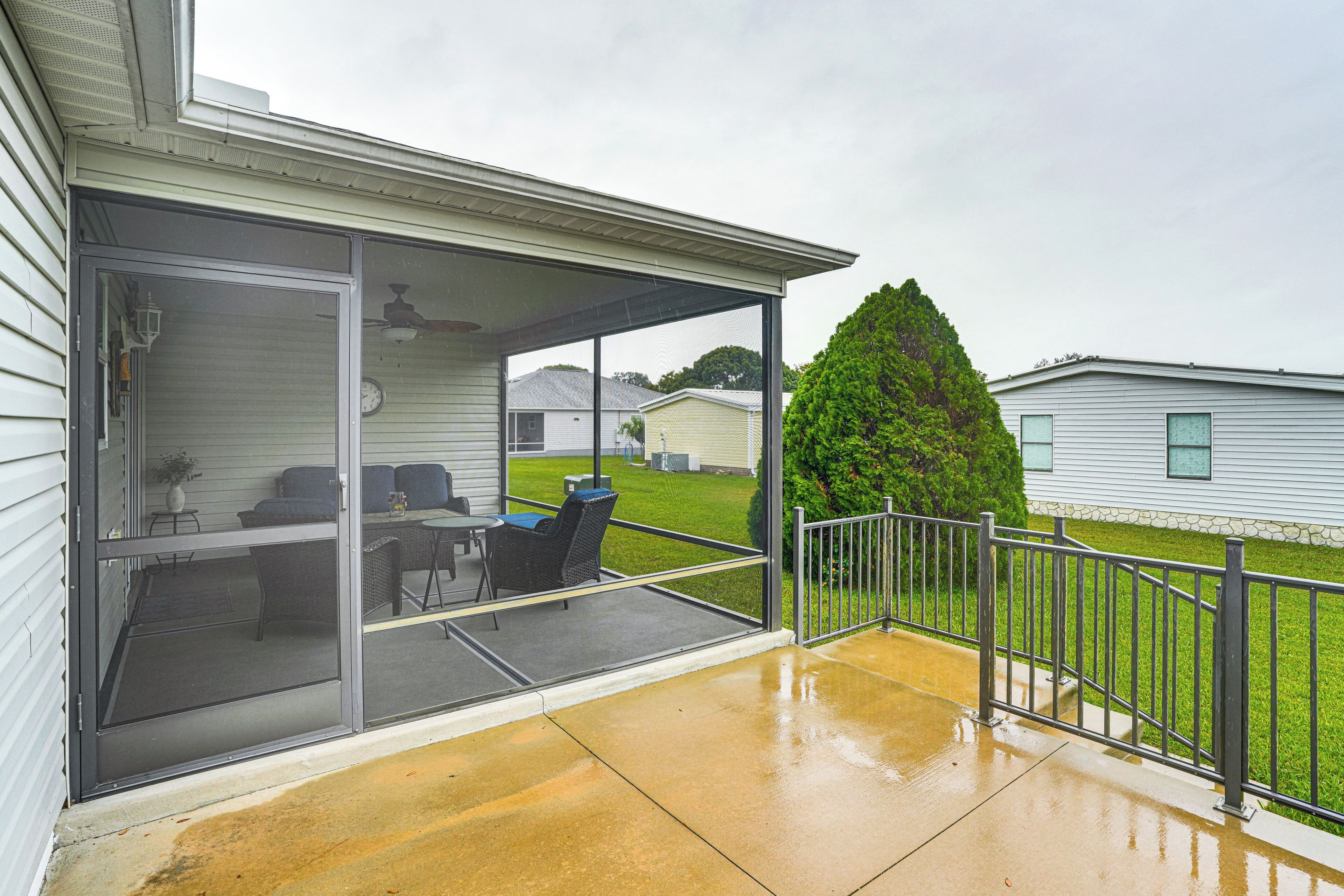 A covered patio with a table and chairs, a sliding glass door, and a metal railing.