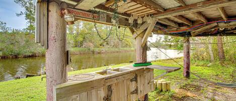 A rustic wooden structure with a sink and a bench, located near a body of water.