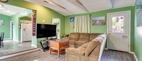 A living room with a sofa, television, and wooden cabinet.