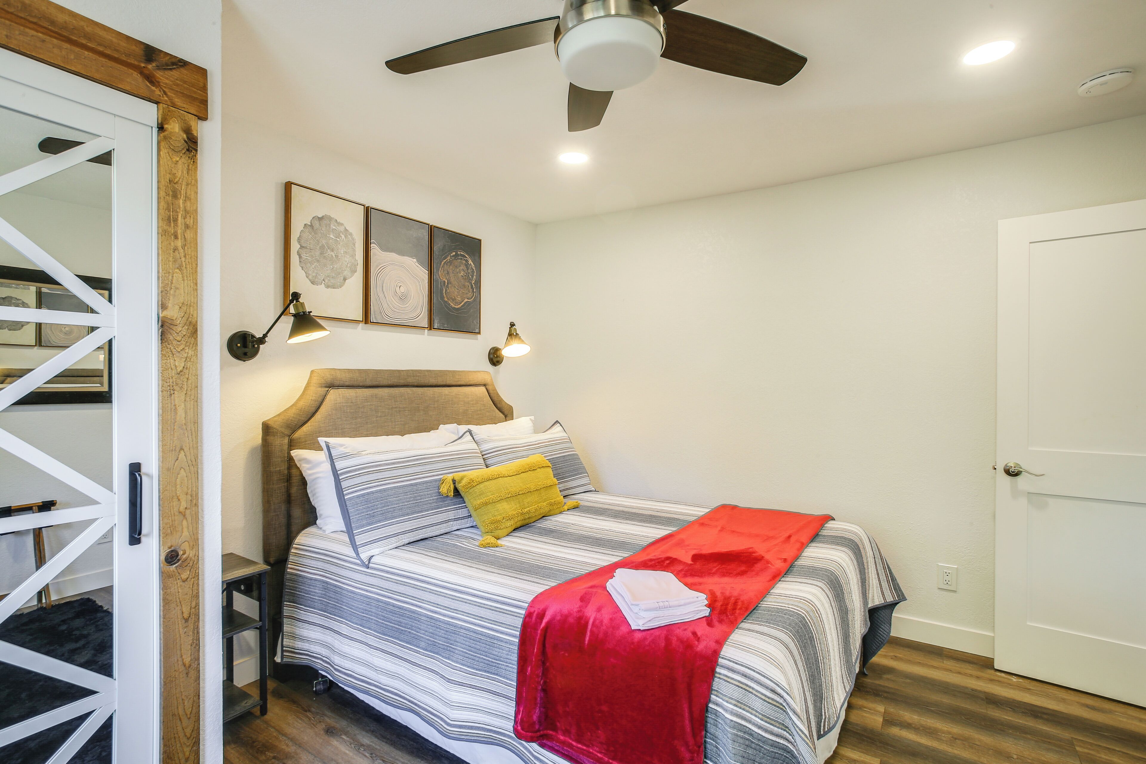 A bedroom with a bed, a ceiling fan, and a door.