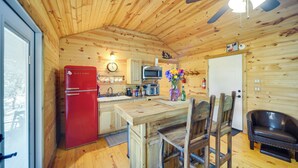 Ein Interieur einer Holzhütte mit Küchenbereich, einschließlich eines roten Kühlschranks, einer Mikrowelle und einer Holztresen.