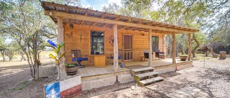 Une cabane en bois avec une véranda, une terrasse et un drapeau.