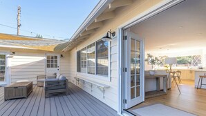 Une maison moderne dotée d’une terrasse, d’une porte-fenêtre coulissante donnant sur la cuisine et d’un patio aménagé avec du mobilier d’extérieur.