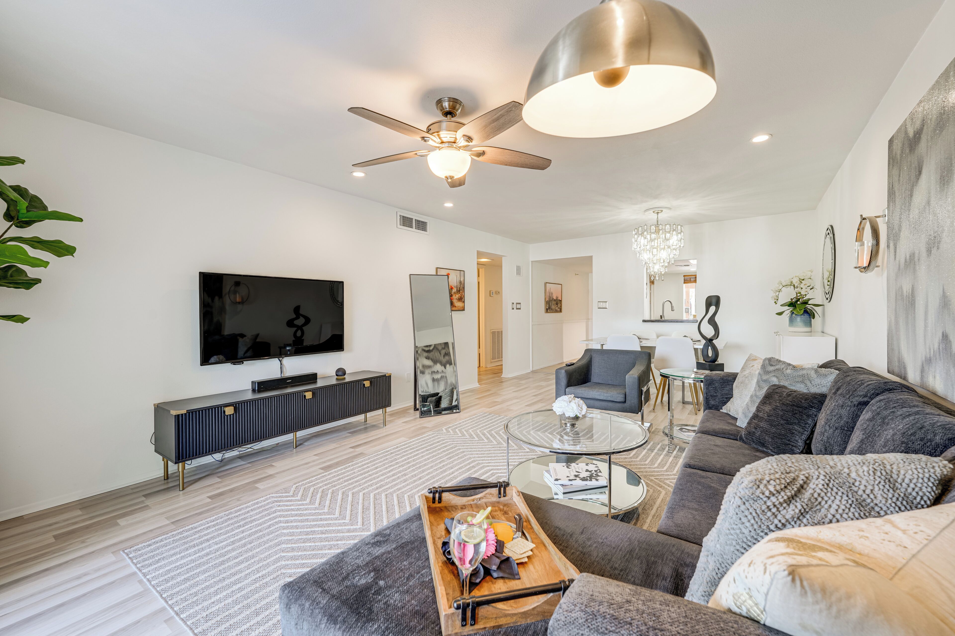 A modern living room with a large sofa, a coffee table, a TV, and a ceiling fan.