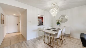 A modern dining area with a marble table, white chairs, a chandelier, and a kitchen in the background. - Furnished Patio, Pool Access! Scottsdale Retreat (Scottsdale)