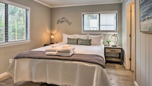 Une chambre à coucher comprenant un lit, deux tables de chevet, un ventilateur de plafond et une fenêtre avec des stores.