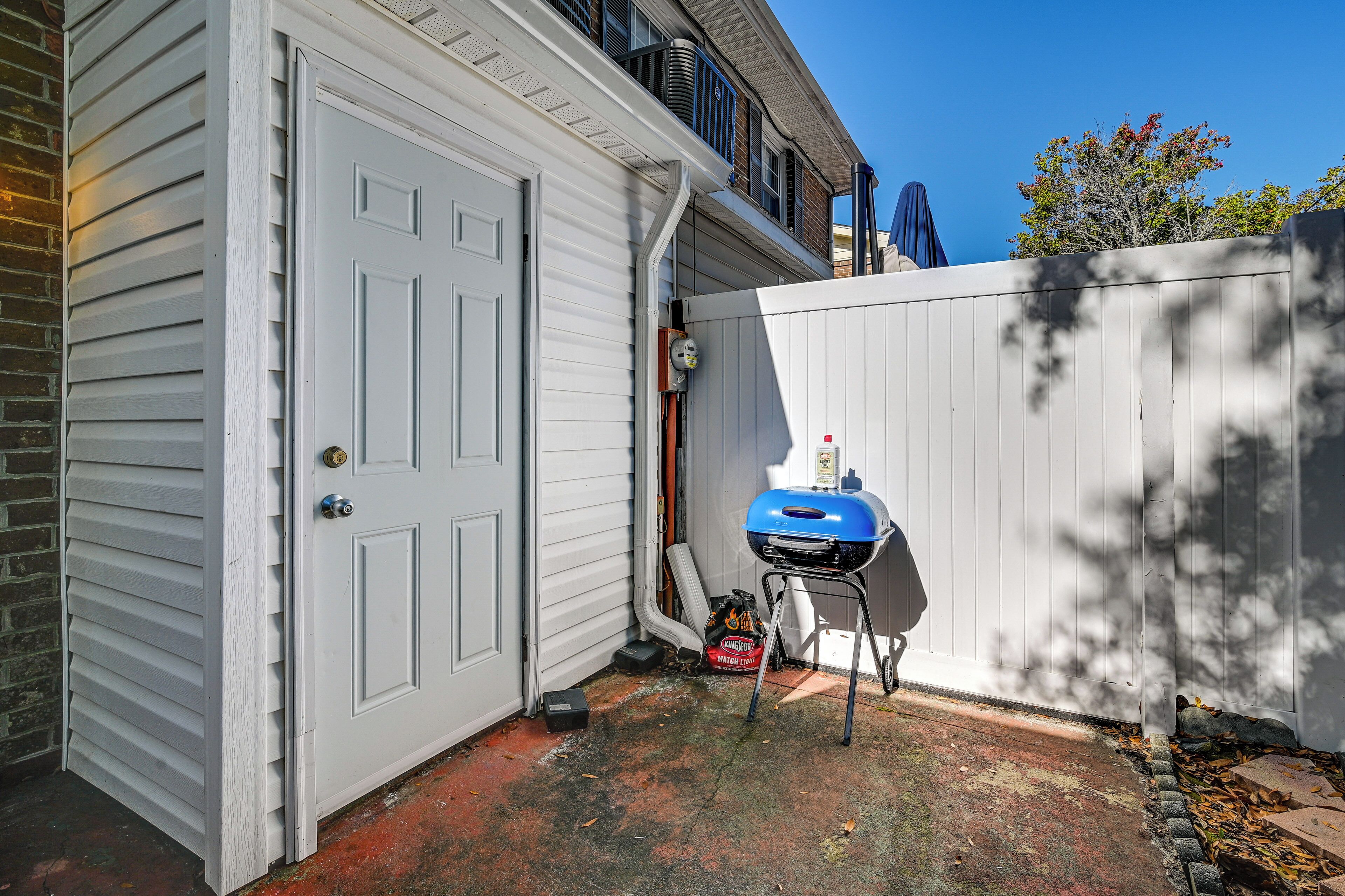 Un garage avec une porte blanche, un barbecue et un sac de charbon de bois.