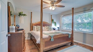 A four-poster bed with a wooden headboard, a ceiling fan, and a large window with blinds. - Walk to Ocean - Townhome w/ Patio in Myrtle Beach! (Myrtle Beach)