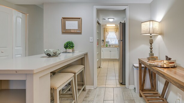 A kitchen with a white countertop, a wooden table with a lamp, and a framed picture on the wall. - Walk to Ocean - Townhome w/ Patio in Myrtle Beach! (Myrtle Beach)