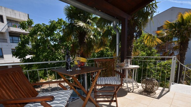 A balcony with wooden furniture, a small table, and a chair.