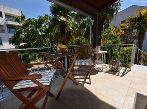 Ein Balkon mit Holzmöbeln, einem kleinen Tisch und einem Stuhl.