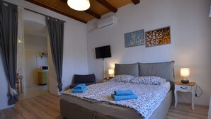 A bedroom with a large bed, a TV, and artwork on the wall.