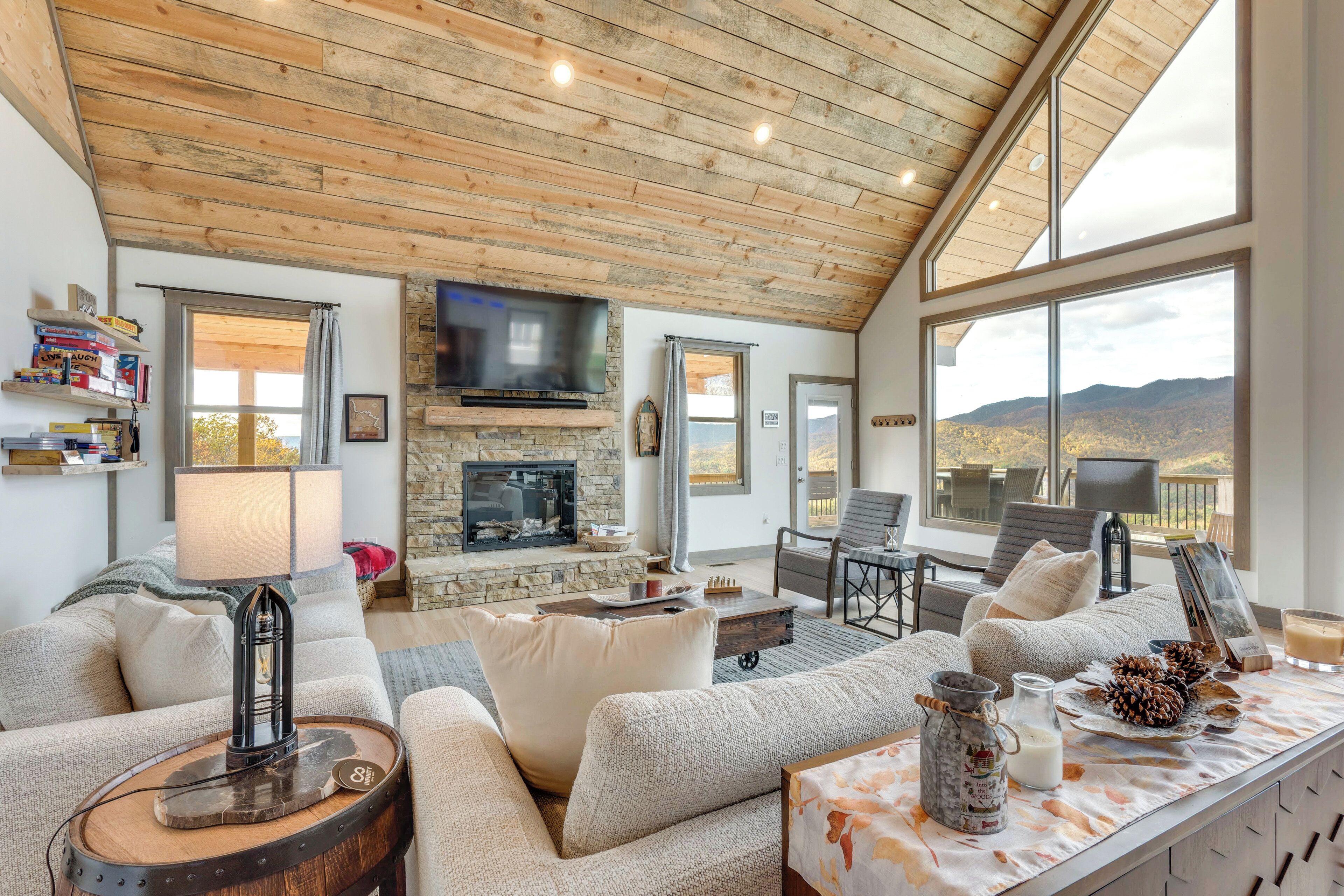 A cozy living room with a stone fireplace, comfortable seating, and large windows offering a mountain view.