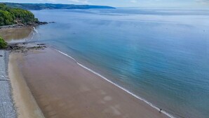 A coastal beach with a sandy shore, calm sea, and distant hills. - Harbour Hideaway - 1 Bedroom Apartment - Saundersfoot (Saundersfoot)