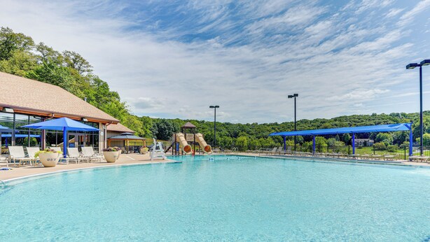 Une piscine avec un toboggan, des chaises longues et des parasols.