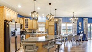 Une cuisine moderne avec des meubles en bois, des appareils en acier inoxydable et un îlot central doté de tabourets de bar.