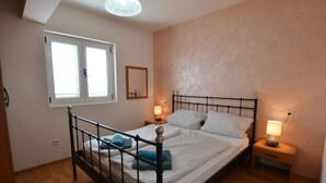 A bedroom with a bed, bedside lamps, a window, and a mirror. - Spacious Apartment With Loggia (Rovinj)
