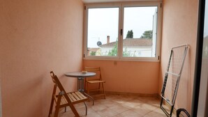 A small balcony with a table and chairs, a window, and a drying rack. - Spacious Apartment With Loggia (Rovinj)