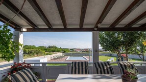 A covered patio with a pool, outdoor seating, and a view of the surrounding landscape. - House Rose With Garden and Pool (Razanac)