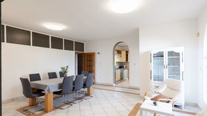 A modern apartment with a dining area, kitchen, and living space. - House Rose With Garden and Pool (Razanac)