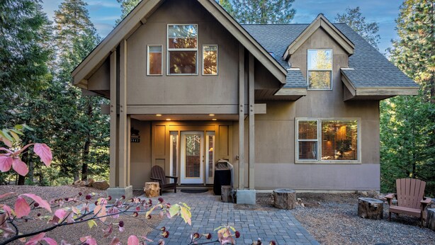 A two-story house with a front porch, a covered entryway, and a small outdoor seating area with Adirondack chairs.