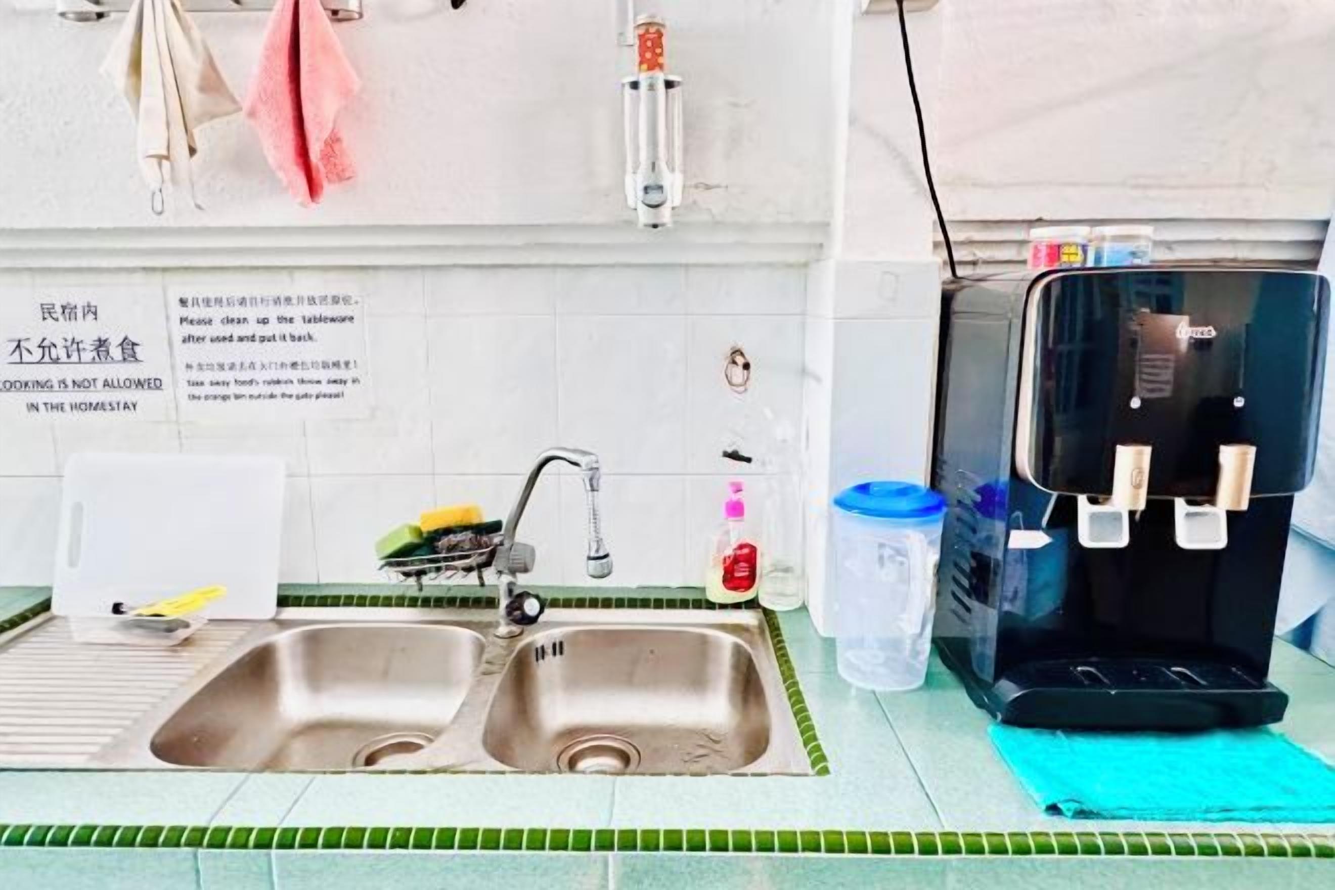 A kitchen with two sinks, a water dispenser, and a sign indicating no cooking is allowed.