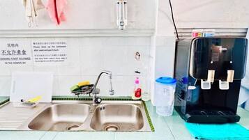 A kitchen with two sinks, a water dispenser, and a sign indicating no cooking is allowed.