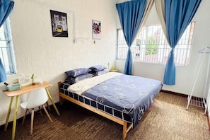 Een slaapkamer met een bed, een bureau en een stoel.