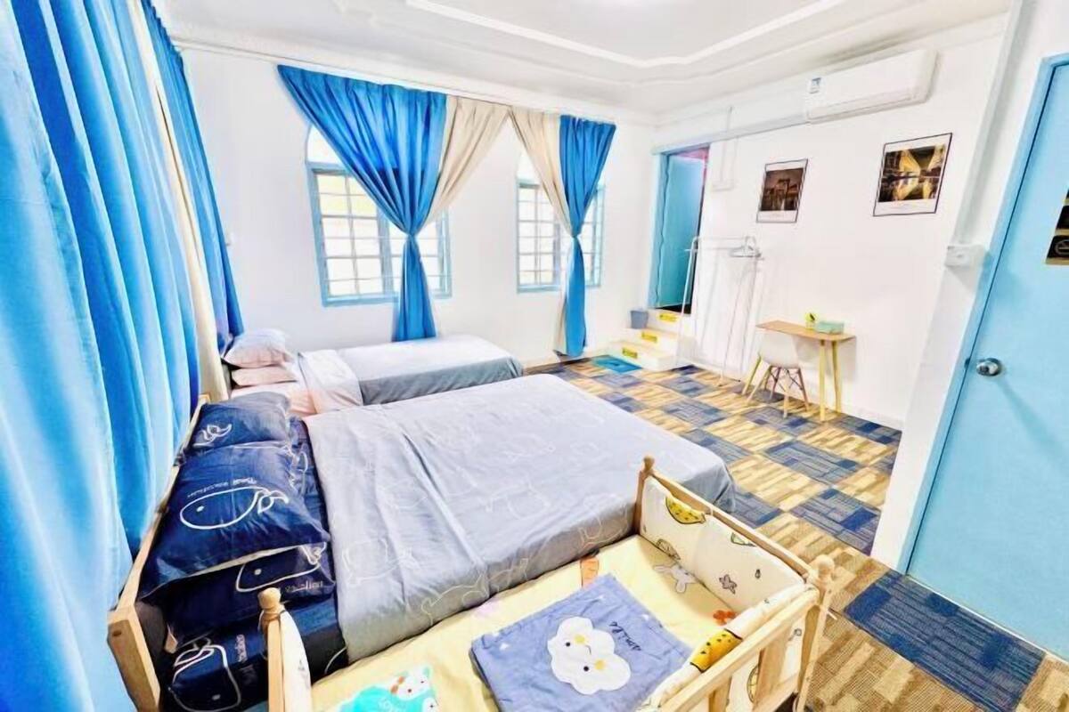 A bedroom with two beds, a bedside table, a chair, a small table, and a door.