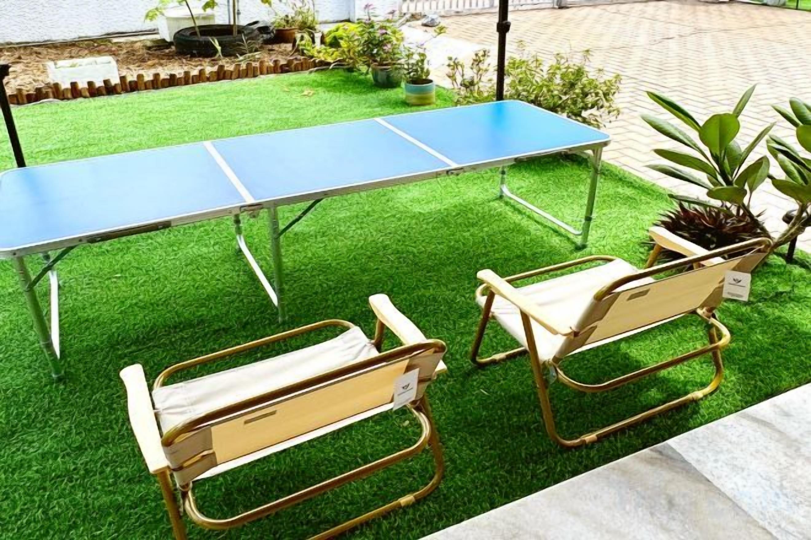 A ping pong table with two chairs on artificial grass.