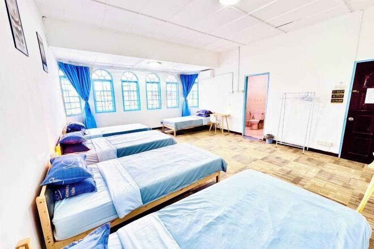 A dormitory room with bunk beds, a desk, a chair, and a window with curtains.
